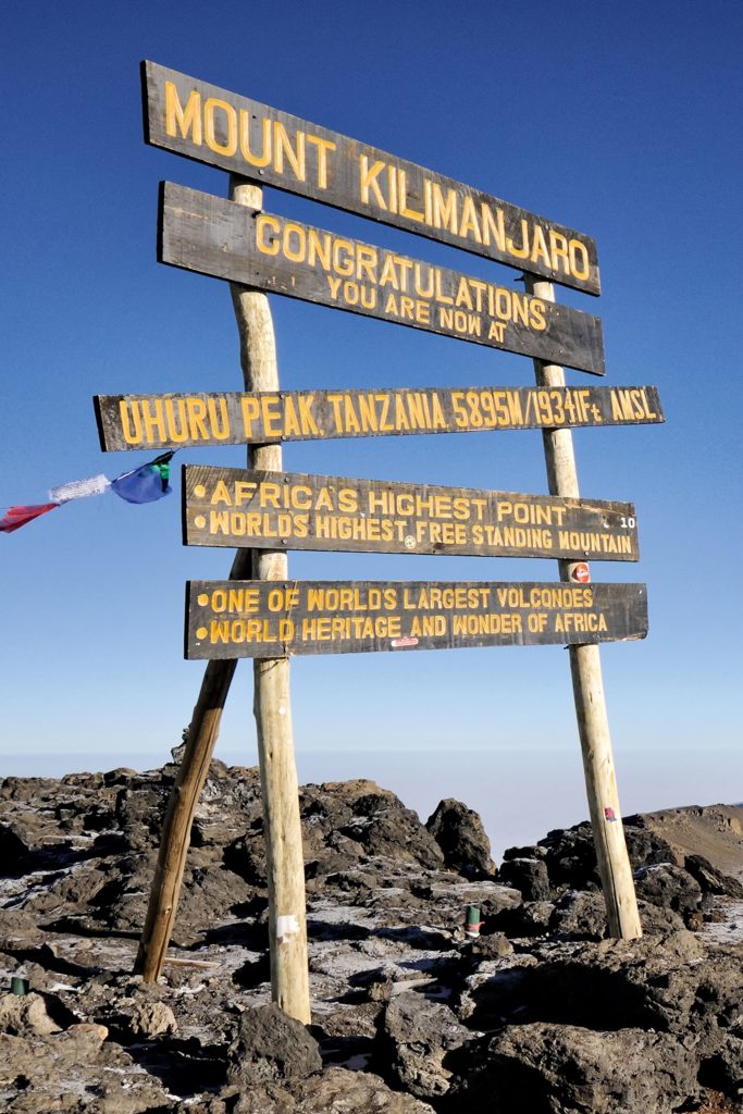 Africa’s highest points are pointed out on mount kilimanjaro summit with wooden hand-painted signs